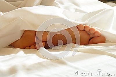 Feet in white bedding Stock Photo