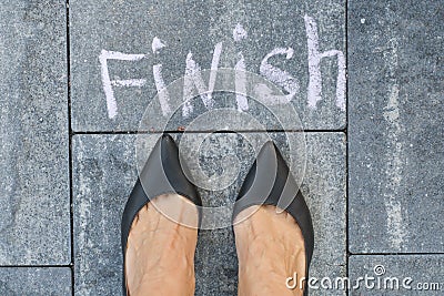 The feet of a woman in black classic shoes before the word finis Stock Photo