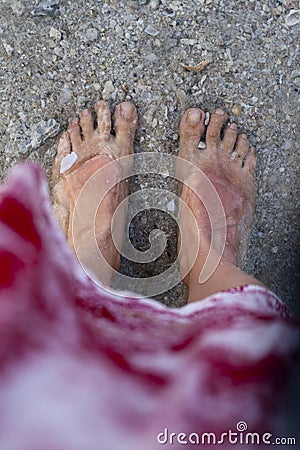 Sunburnt feet of a woman in transparent ocean water. Sand and shells. Stock Photo