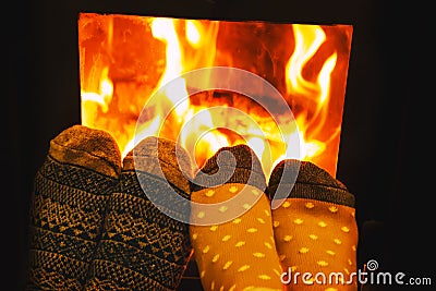 Feet in wool socks of couple lovers warming by cozy fire. Stock Photo