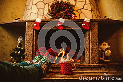 Feet in woollen socks by the Christmas fireplace. Woman relaxes Stock Photo