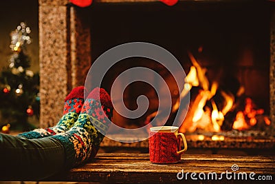 Feet in woollen socks by the Christmas fireplace. Woman relaxes Stock Photo