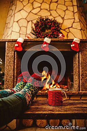 Feet in woollen socks by the Christmas fireplace. Woman relaxes Stock Photo