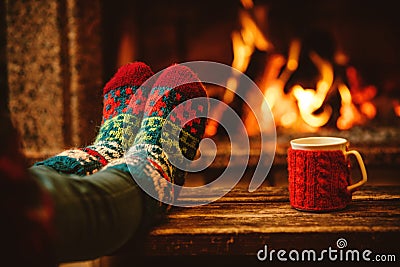 Feet in woollen socks by the Christmas fireplace. Woman relaxes Stock Photo