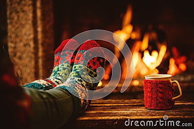 Feet in woollen socks by the Christmas fireplace. Woman relaxes Stock Photo