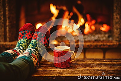 Feet in woollen socks by the Christmas fireplace. Woman relaxes Stock Photo