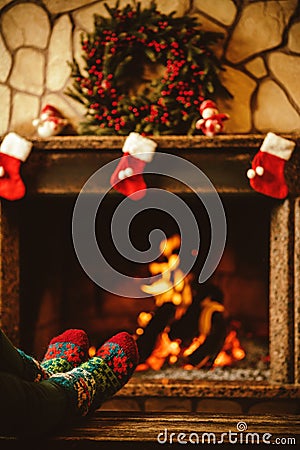 Feet in woollen socks by the fireplace. Woman relaxes by warm fi Stock Photo