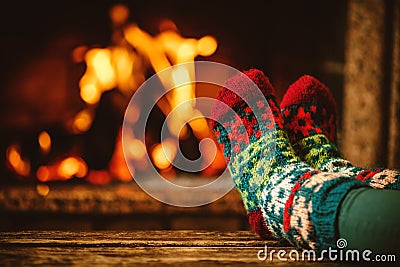 Feet in woollen socks by the fireplace. Woman relaxes by warm Stock Photo