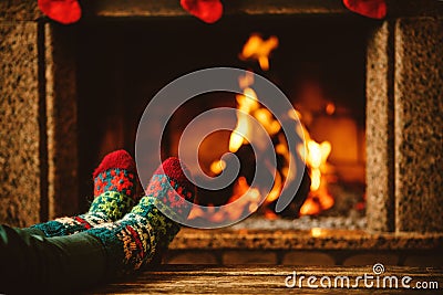 Feet in woollen socks by the fireplace. Woman relaxes by warm Stock Photo