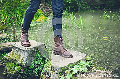 Feet of young person on stepping stones in a pond. Stock Photo