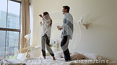 Felice e divertente coppia di giovani famiglie che ballano saltando sul materasso da letto stock footage Felice e divertente coppia di giovani famiglie che ballano saltando sul materasso da letto stock footage