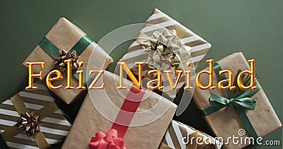 Feliz navidad text in orange over christmas gifts on green background Stock Photo