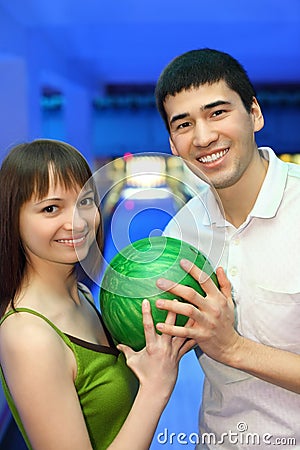 Fellow and girl turned to each other and hold ball Stock Photo