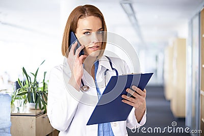 Femal doctor having a call while standing in medical clinic Stock Photo