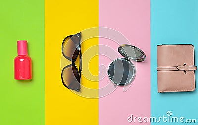 female accessories on a colored background. Sunglasses, bottle of perfume, mirror, purse. Top view. Flat lay Stock Photo