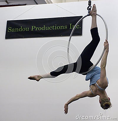 A female acrobat swings upside down from an aerial hoop. Editorial Stock Photo