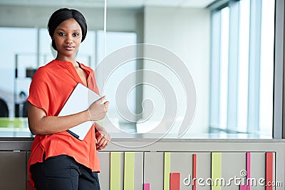 Female African entrepreneur holdiing a tablet while looking at camera Stock Photo