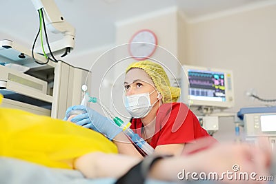 Female anesthesiologist injects anesthesia into patient face mask. General sedation while surgery operation. Paramedic putting Stock Photo