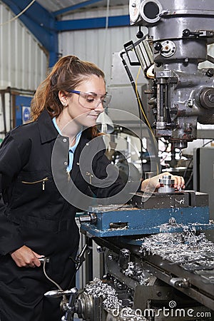 Female Apprentice Engineer Working On Drill In Factory Stock Photo