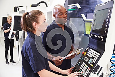 Female Apprentice Working With Engineer On CNC Machinery Stock Photo