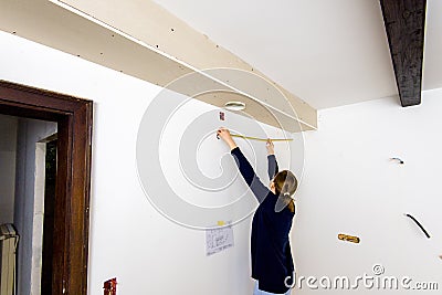 Female architect measuring with yellow tape the length from the cooker hood Stock Photo