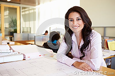 Female Architect Studying Plans In Office Stock Photo