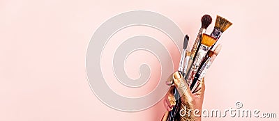 Female Artist golden hand with set of brushes. Banner format Stock Photo