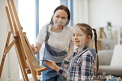 Female artist teaching girl funny shapes by guiding her hand Stock Photo