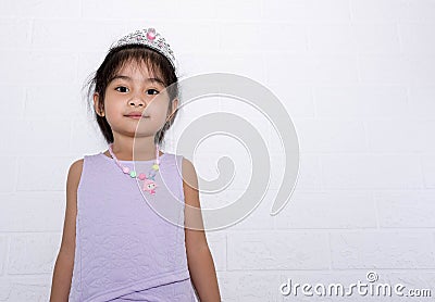 Female asian child girl standing with white background wearing accessories, crown and necklace purple dress Stock Photo