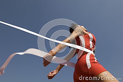 Female Athlete Crossing Finish Line Against Blue Sky Stock Photo