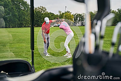 Female athlete in a face mask learning golf swing fundamentals Stock Photo