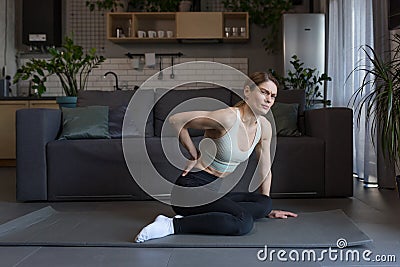 A female athlete injured her back during morning exercises at home Stock Photo