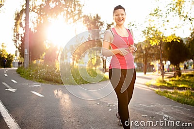 Female athlete jogging around the park at sunset Stock Photo