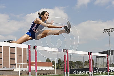 Female Athlete Jumping Over A Hurdles Stock Photo