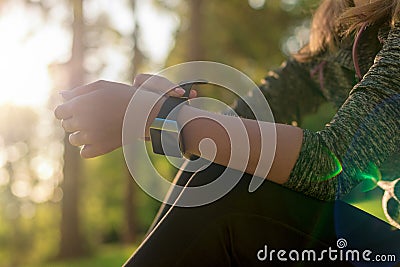 Female athlete putting on her her smart watch to monitor workout performance. Lifestyle wearable technology concept. Stock Photo