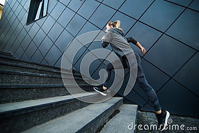 Female athlete running fast up the stairs staircase workout Stock Photo