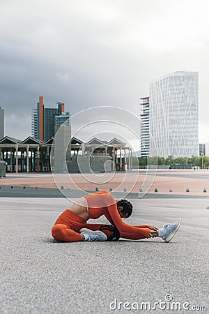 Female athlete stretching leg before running. Young caucasian woman morning workout routine. Vertical image Stock Photo