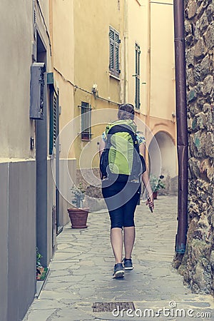 Female backpacker exploring narrow streets of medieval town. Stock Photo