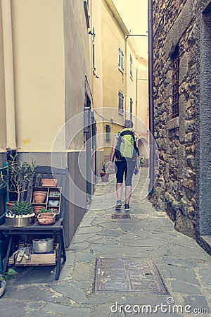 Female backpacker exploring narrow streets of medieval town. Stock Photo