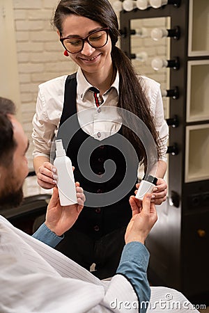 Female in the barbershop demonstrates male care products Stock Photo