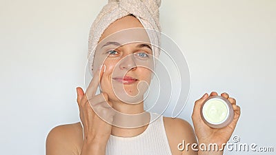 Female beauty routine. Moisturizing cream jar. Clean and smooth skin. Spa skincare regimen. Cute young woman applying cream on her Stock Photo