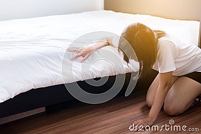 Woman bent and searching something under bed lost thing Stock Photo