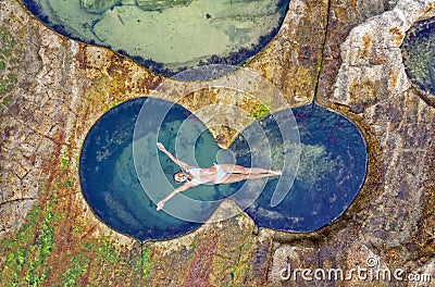 Female floating in idyllic ocean rock pool just bliss Stock Photo