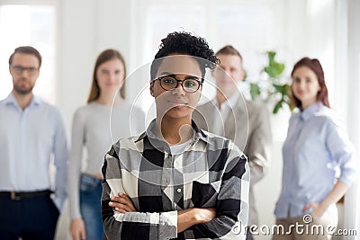 Female black millennial employee standing foreground arms crosse Stock Photo