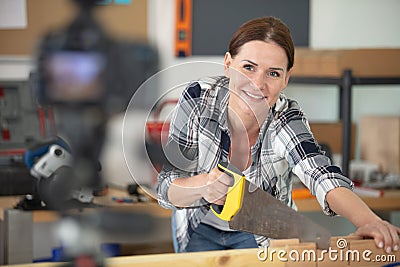 Female blogger cutting plank with saw Stock Photo