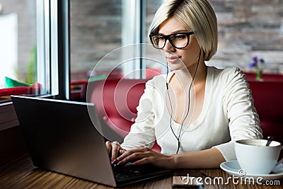 Female Blogger Wearing Glasses While Using Laptop In Cafe Stock Photo