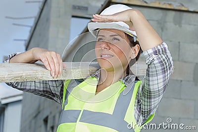 female builder carrying wood on site Stock Photo