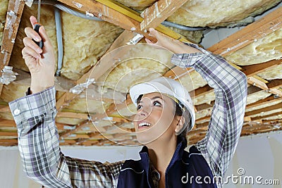 Female builder using screwdriver on roof renovation Stock Photo
