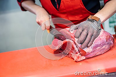 Woman cutting fresh meat in a butcher shop with metal safety mes Stock Photo