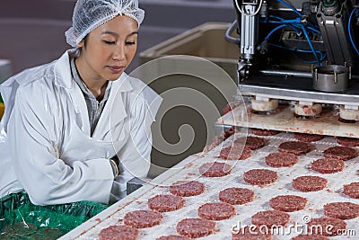 Female butcher processing hamburger patty Stock Photo